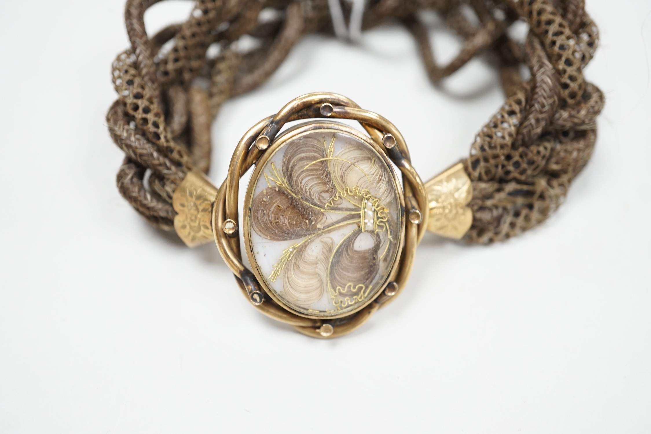 A 19th century gilt metal and plaited hair set interwoven hair mourning bracelet, central motif 41mm by 33mm.